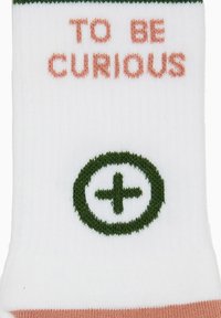 Calze bianche con accenti verdi e pesca, con la scritta "TO BE CURIOUS" in pesca e un logo a segno più verde.