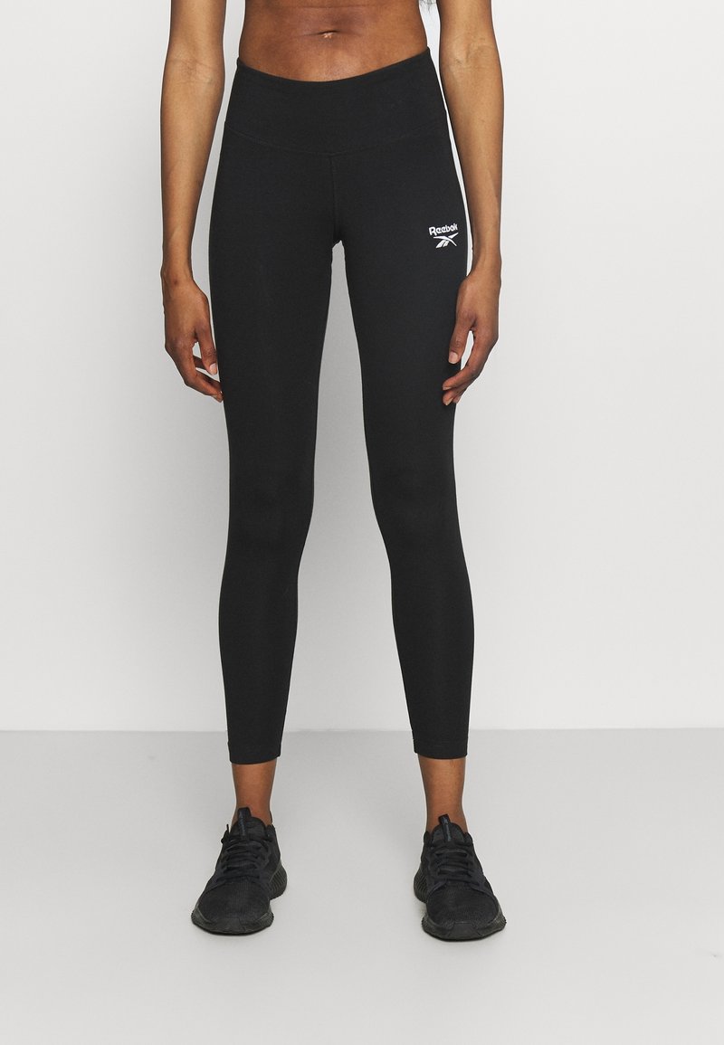 Svarta tights i stretchmaterial, med hög midja och en liten vit logotyp på vänster lår. Slät textur, figurnära design.