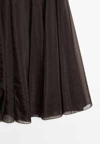 Tessuto trasparente marrone scuro con cuciture verticali, che scorre con una texture leggermente lucida e un aspetto leggero.