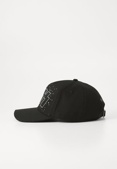 Svart caps med buet skjerm, har et grafisk design laget av nagler foran, med en strukturet krone og ventilasjonshull.
