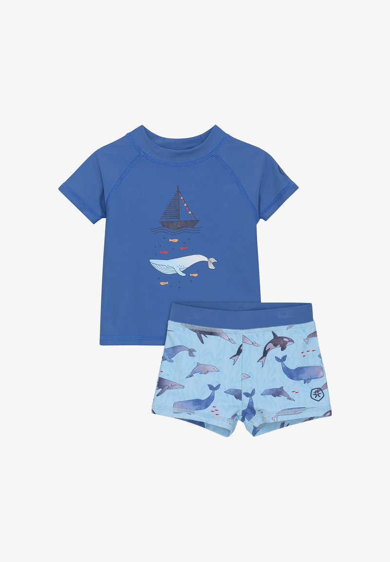 Le rash guard bleu à manches courtes présente un graphique de bateau et de baleine. Accompagné d'un short de bain bleu clair avec des motifs de dauphins et de baleines.