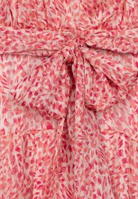 Lätt, rosa mönstrad tyg med abstrakta penseldrag. Har en knut i midjan och lager av textur.