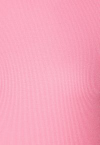 Růžová ribbed látka s hladkým povrchem, která má vertikální vzory. Celkový design je přiléhavý a elastický, vhodný pro různé účely.