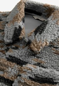 Texturierte Fleecejacke mit einer Mischung aus Grau-, Braun- und Schwarztönen, mit Kragen und Knopfdetail. Weiches, samtiges Material.