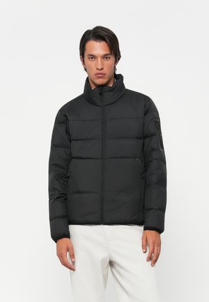 Casaco puffer preto com gola alta, costura horizontal, fecho de zip e bolsos laterais, apresentando um acabamento mate e design minimalista.