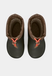 Une paire de bottes en caoutchouc vert foncé avec un doublure marron et des cordons orange, vues d'en haut sur un fond blanc.