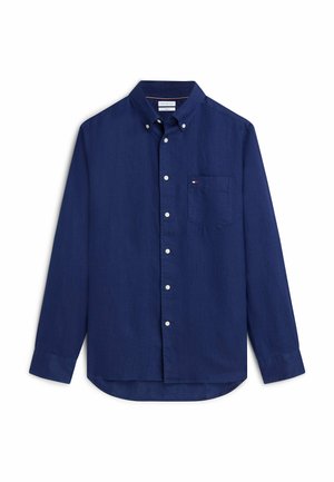 Chemise bleu marine à manches longues avec poche poitrine et boutons blancs, étalée à plat sur fond blanc.