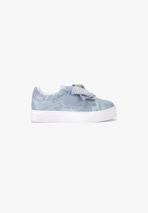 Sneaker in velluto azzurro chiaro con suola in gomma bianca, decorata con un grande fiocco e borchie argentate sul tallone, caratterizzata da una superficie liscia.