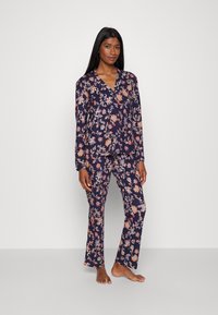 Blommig pyjamasset med marin bakgrund, långärmad knäpp-up topp och matchande byxor med ett färgglatt blommönster. Slät tyg.