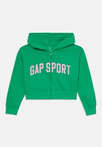Zelená krátka mikina s kapucňou vyrobená z bavlnenej zmesi, obsahujúca plný zips, šnúrku na kapucni a text "GAP SPORT" v ružovej farbe cez hruď.
