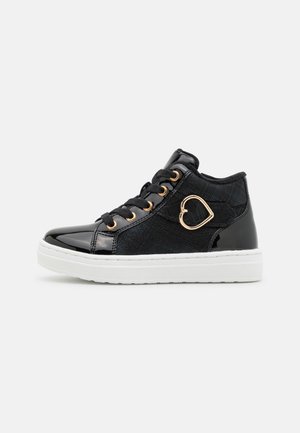 Zapatillas negras de caña alta con cuero sintético y tejido texturizado. Presentan herrajes en forma de corazón en tono dorado, cordones negros y suela de goma blanca.