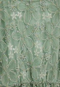 Lysegrønt stof med blomsterbroderi i tyl, pyntet med guldtråd. Indeholder pailletter og teksturerede blomsterformer over det hele.