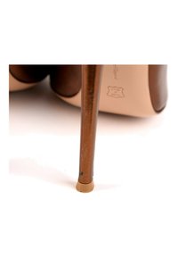 Chaussure à talon haut marron avec un talon fin et une semelle beige reposant sur une surface blanche.