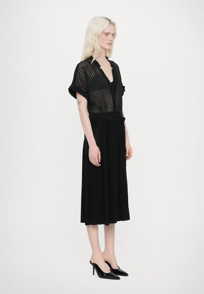 Vestido midi negro con un profundo escote en V, mangas cortas y cintura ceñida con cinturón. Presenta un diseño a rayas y una tela fluida con una textura suave.