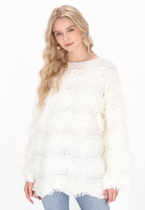 Pull en tricot blanc avec un design à franges superposées et des manches à cloche ; motif texturé avec des sections en tricot ouvert ; coupe décontractée.