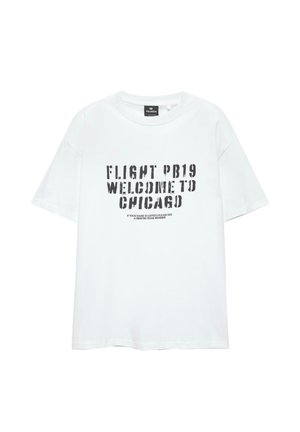T-shirt bianco in cotone con maniche corte e colletto tondo. Presenta un testo nero: "FLIGHT PB19 WELCOME TO CHICAGO" in un carattere audace e logorato.