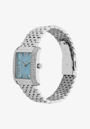 Silverfärgad metallklocka med en rektangulär glittrande bezel och en ljusblå urtavla. Har romerska siffror och ett strukturerat armband. Märkt "Michael Kors."