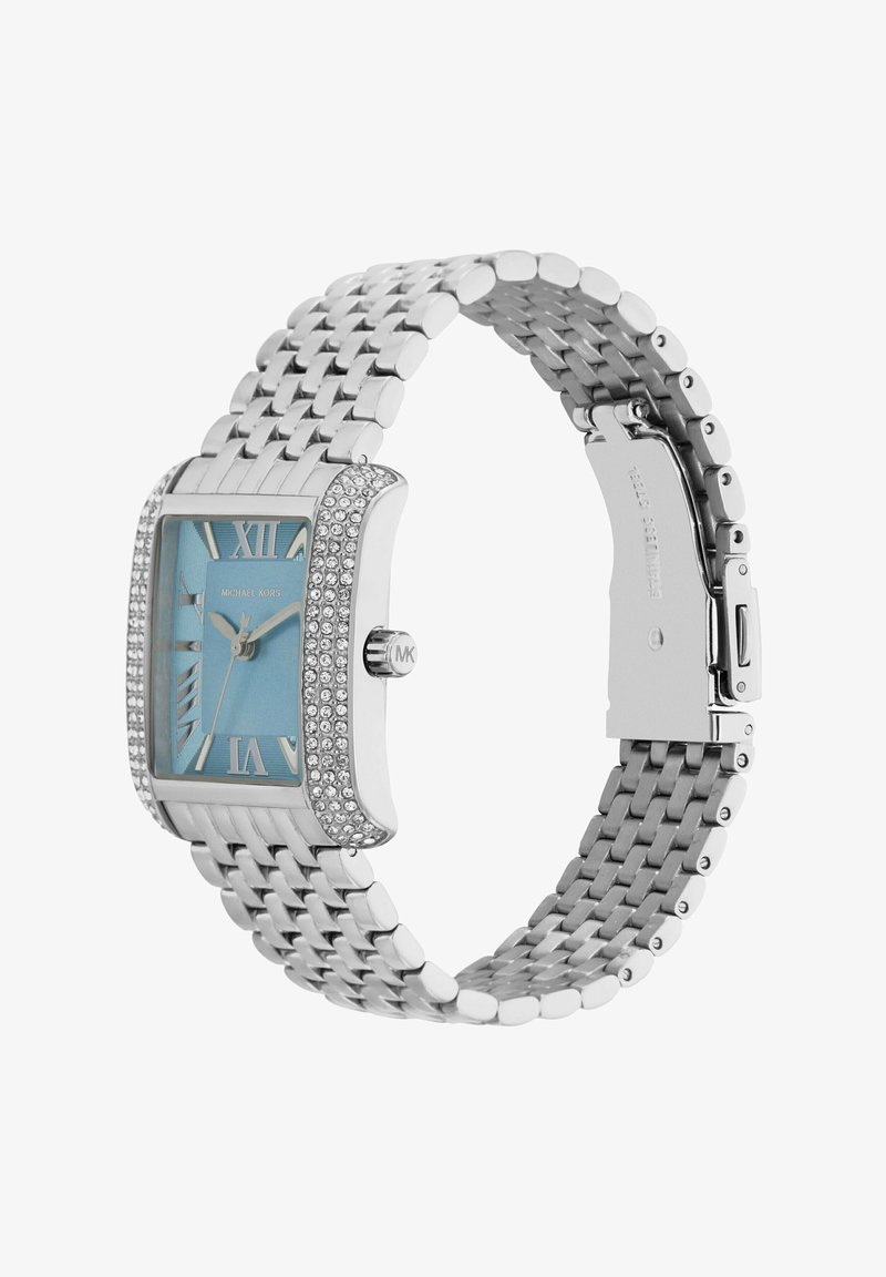 Srebrny metalowy zegarek z prostokątną, błyszczącą ramką i jasnoniebieską tarczą. Posiada rzymskie cyfry oraz teksturowany pasek. Oznaczony "Michael Kors."