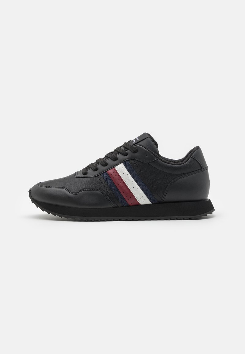 Sneaker in pelle nera con tre strisce orizzontali in rosso, bianco e blu, superficie testurizzata, suola in gomma nera piatta, design a taglio basso.
