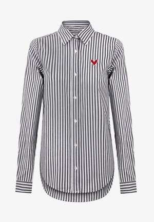 Camisa de botones con rayas verticales en blanco y negro, que presenta un bordado de un corazón rojo en el lado izquierdo del pecho. Mangas largas y dobladillo curvado.