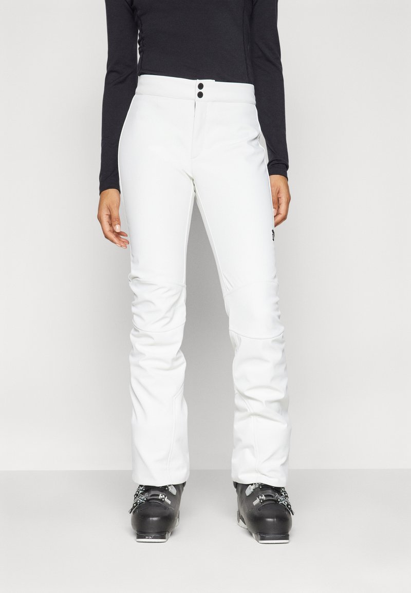 Witte skibroek met een gladde textuur en een strakke pasvorm, met een knopen tailleband en zwarte accenten, gedragen met zwarte skischaatsen.