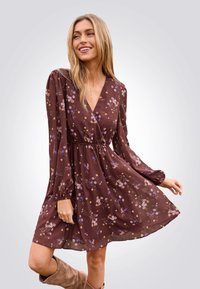 Braunes Blumenkleid mit langen, puffigen Ärmeln und tiefem V-Ausschnitt. Es hat eine taillierte Taille und einen fließenden Rock, der mit kleinen bunten Blumen verziert ist.
