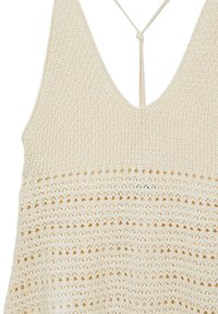 Top tricoté de couleur crème avec un décolleté en V profond. Présente des motifs texturés verticaux et de petites découpes circulaires sur toute la surface. Se noue au dos.