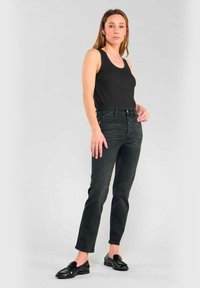 Svart linne kombinerat med högmidjade, mörka denimjeans. Jeansen har en klassisk passform och något stretchigt material med framfickor. Svarta loafers fulländar looken.