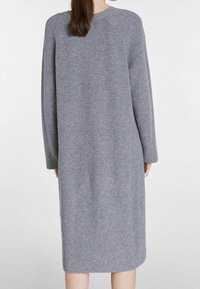 Abito in maglia grigia con maniche lunghe, texture a coste, taglio dritto e scollo rotondo, che arriva sotto il ginocchio.