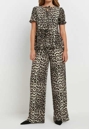 Ensemble deux pièces imprimé léopard comprenant un haut à manches courtes avec un nœud au cou et un pantalon à jambes larges. Le tissu est doux avec une texture lisse.
