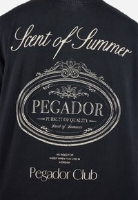 Tricou negru cu text alb și elemente decorative. Textul include "Scent of Summer", "PEGADOR" și "Pegador Club" în diverse stiluri.