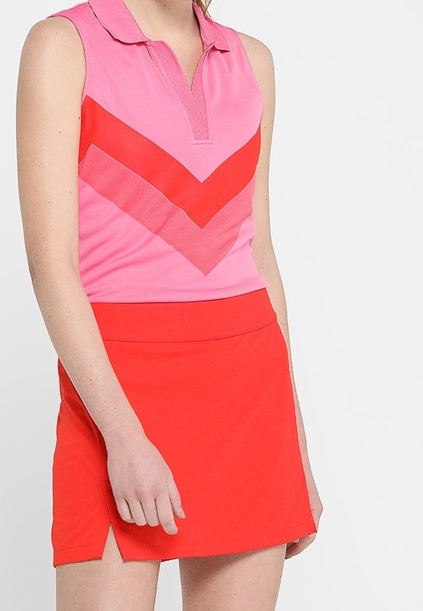 Ärmlös pikétröja i rosa med rött chevronmönster, kombinerad med en enfärgad röd skirtshorts. Båda tillverkade av andningsbart tyg.