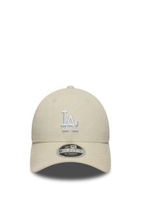 Beige basebollkeps med texturerad tyg, som har en vit broderad "LA"-logotyp på framsidan, justerbart baksnöre och böjd skärm.