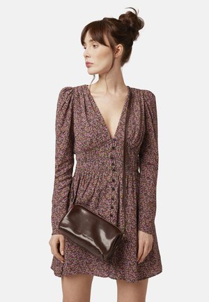 Abito floreale in tonalità di rosa e viola, con vita arricciata e lunghe maniche a sbuffo. Borsa a tracolla marrone scuro con texture liscia.