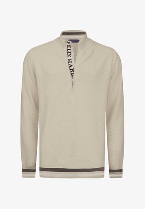 Pull en beige clair avec un motif texturé, zip quart, et ourlet à bande. Présente un détail de logo contrastant sur le col.