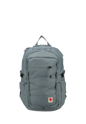 Zaino grigio ardesia con cordino elastico frontale, fibbie laterali, manico superiore e una piccola toppa con logo di volpe rossa vicino al centro inferiore.