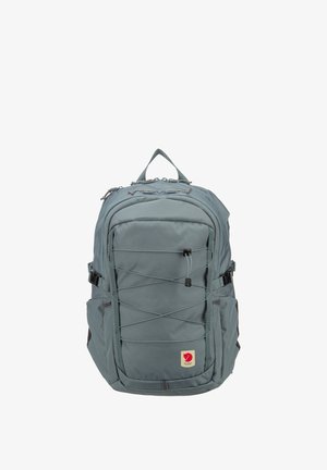 Zaino grigio ardesia con cordino elastico frontale, fibbie laterali, manico superiore e una piccola toppa con logo di volpe rossa vicino al centro inferiore.