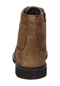 Stivale alla caviglia in suede marrone con dettagli decorativi a brogue, chiusura con zip e suola robusta in gomma nera. Accenti cuciti sulla parte superiore.
