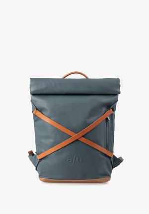Blauer Rolltop-Rucksack mit braunen Leder-Querriemen, einem oberen Griff, seitlicher Reißverschlusstasche und einem geprägten "a/u"-Logo auf der Vorderseite.