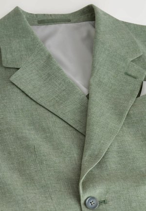 Sacou verde deschis dintr-un material texturat, cu rever decupat, închidere cu un singur nasture și căptușeală interioară gri.