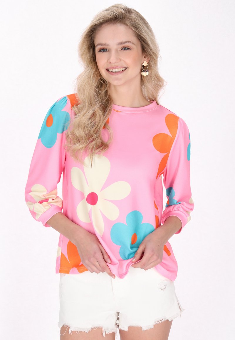Maglietta a maniche lunghe rosa con grandi motivi floreali multicolori in blu, arancione e crema. Tessuto morbido con polsini a sbuffo.