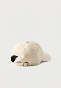 Μπεζ καπέλο μπέιζμπολ από βαμβάκι. Διαθέτει καμπύλη γείσο και ρυθμιζόμενο λουράκι στο πίσω μέρος, με οπές αερισμού και απλή υφή.