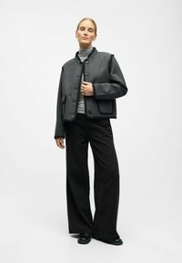 Gray wool-blend jacket with black accents, cropped design, button closure, and large pockets. Paired with wide-leg black pants.