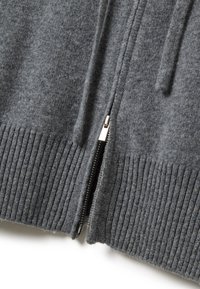 Maglione grigio con zip, con orlo a coste, caratterizzato da una texture di tessuto morbida e liscia e un dettaglio della cerniera metallica sul davanti.