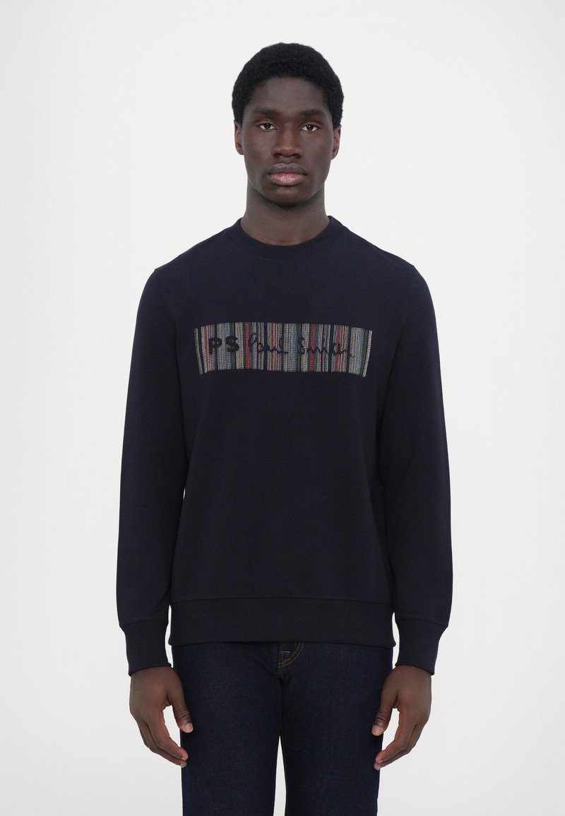 Sweatshirt bleu marine à manches longues, avec un graphique rayé multicolore et du texte sur la poitrine. Matière en mélange de coton.