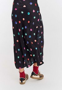 Černá sukně s barevnými vzory srdcí a drahokamů; spárována s leopardími botami a červenými žebrovanými ponožkami. Vyznačuje se plynulou tkaninou.