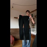 Fekete nadrág elasztikus derékpánttal, egyenes szárú kialakítással és fehér címkével. Az anyag simának tűnik, valószínűleg pamut vagy keverék.