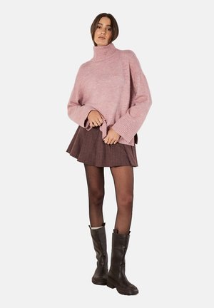 Rosa, oversized Strick-Turtleneck-Pullover mit gerippten Bündchen, kombiniert mit einem braunen karierten Faltenrock und schwarzen knielangen Stiefeln.