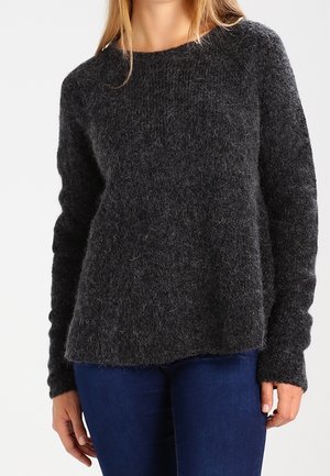 Zwarte, gestructureerde trui met lange mouwen en een ronde hals, gemaakt van een pluizig materiaal, gecombineerd met blauwe denim.