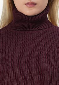Bordeaux turtlenecktröja med ett strukturerat stickat mönster. Har en hög, ribbad hals och en figurnära design.